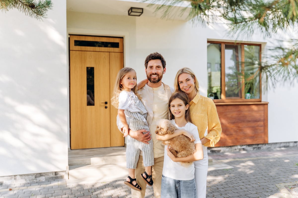 Smiling family with two daughters and small dog posing together in modern house